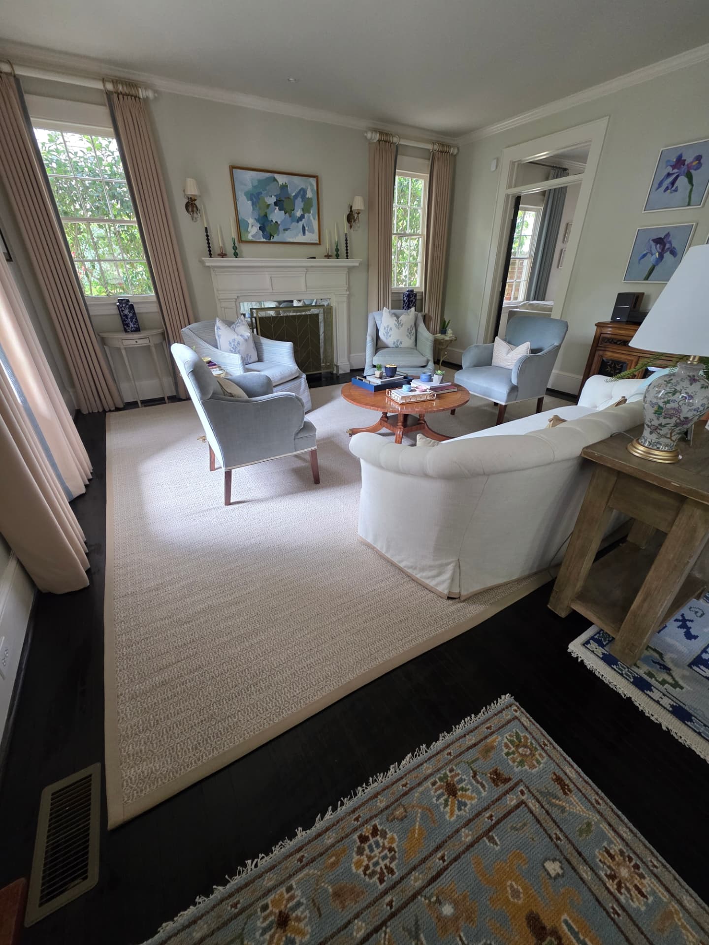 Cleaned living room with fireplace, light blue armchairs and a fresh rug